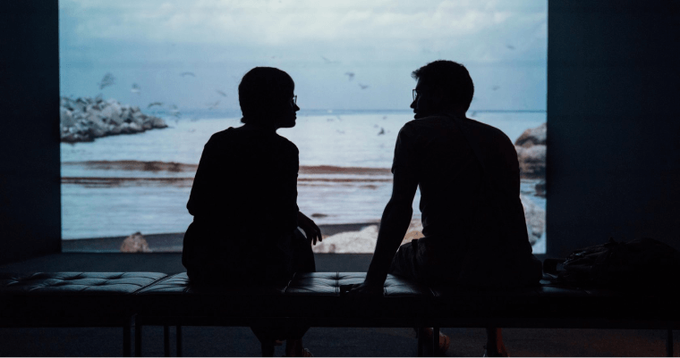 два силуэта разговаривают на фоне моря