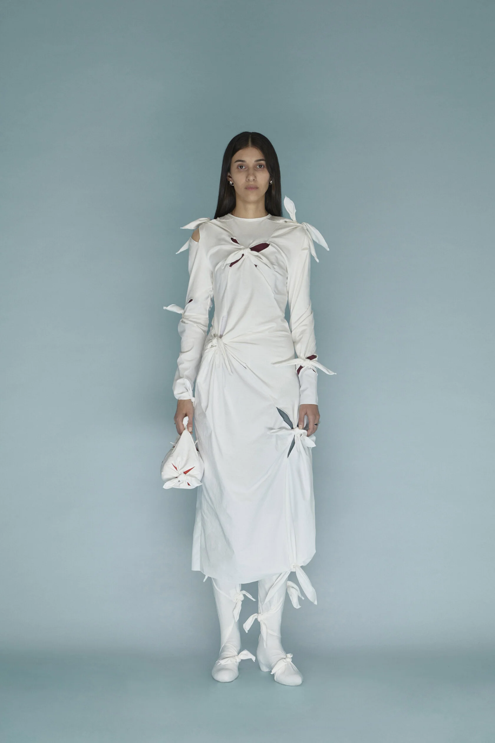Model wears white long sleeve maxi dress with knots pattern designed by J.Kim studio